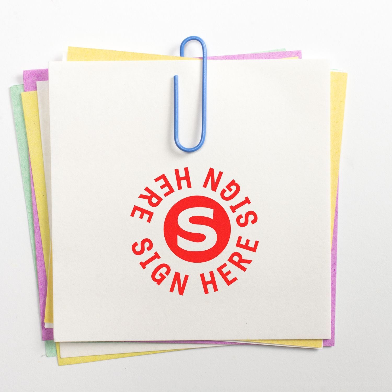 Stack of colorful blank sticky notes clipped with a blue paperclip and Sign Here stamp on white background