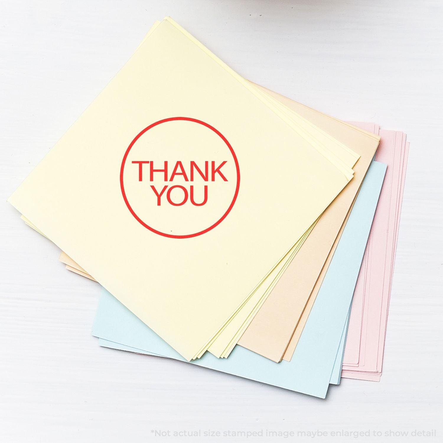 Stack of pastel thank you cards with red thank you stamp on white background.