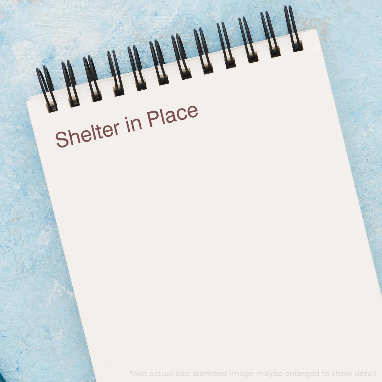 Notepad with Shelter in Place text on a blue background, concept of emergency stay-at-home order and public safety.