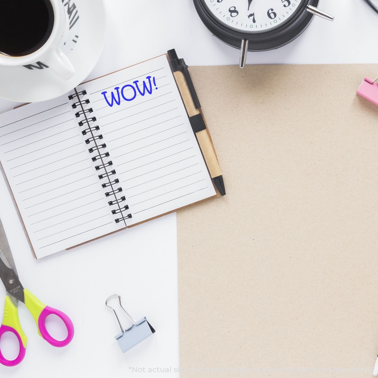 Flat lay of a creative workspace with an open notebook saying WOW, coffee cup, clock, scissors, and office supplies on a clean desk.