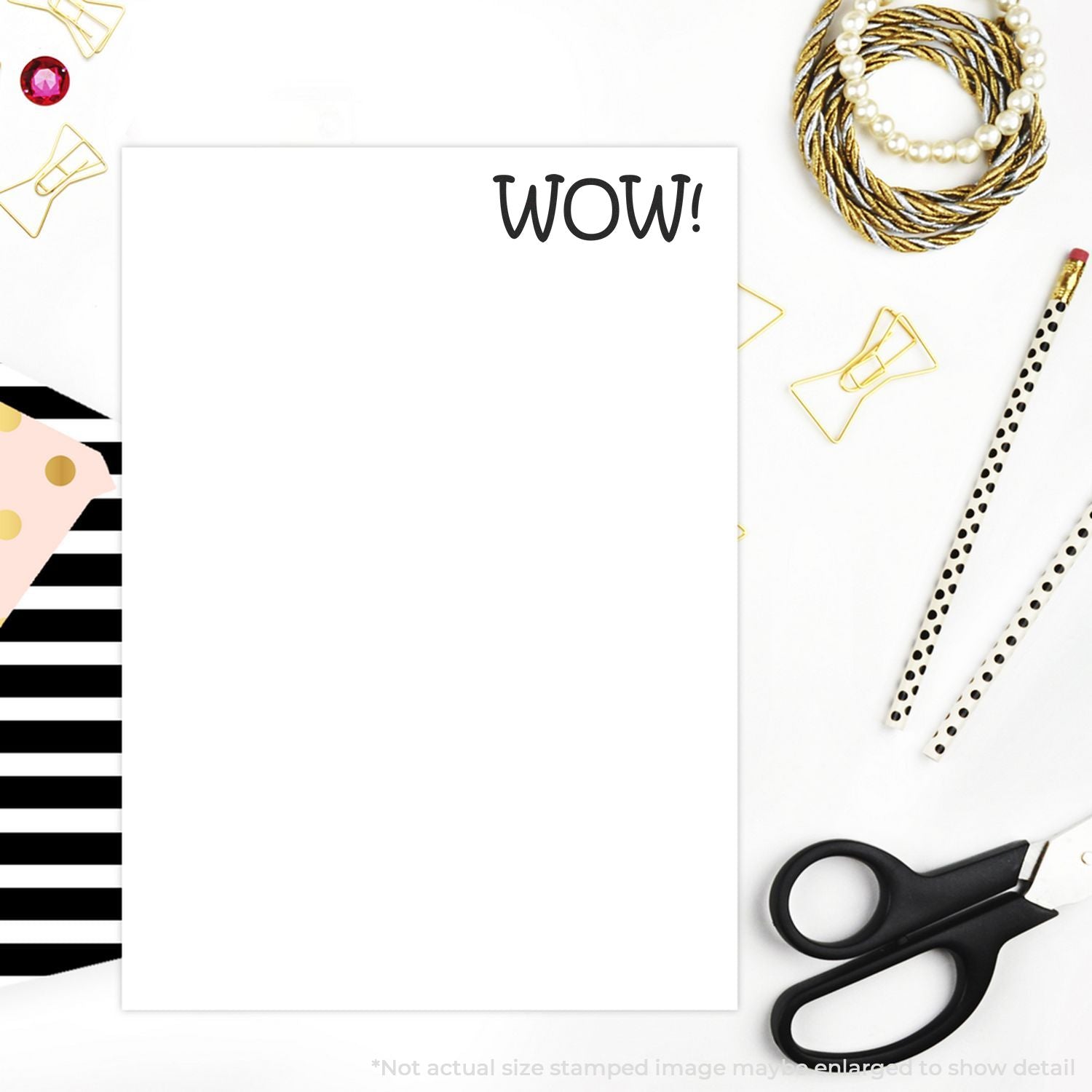 Blank greeting card with WOW! on white background, surrounded by gold paperclips, red jewel, pen, scissorscrafting flat lay template.