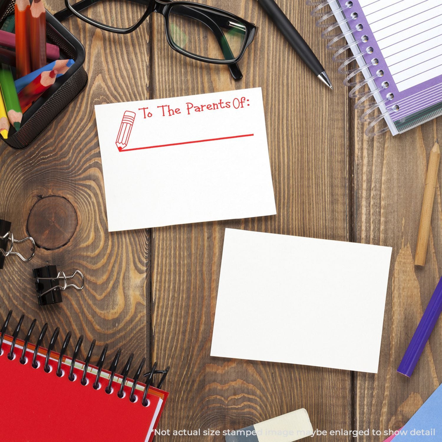 School stationery flat lay with blank note card titled To The Parents Of, pencils, notebook, glasses, and pen on a wooden desk.