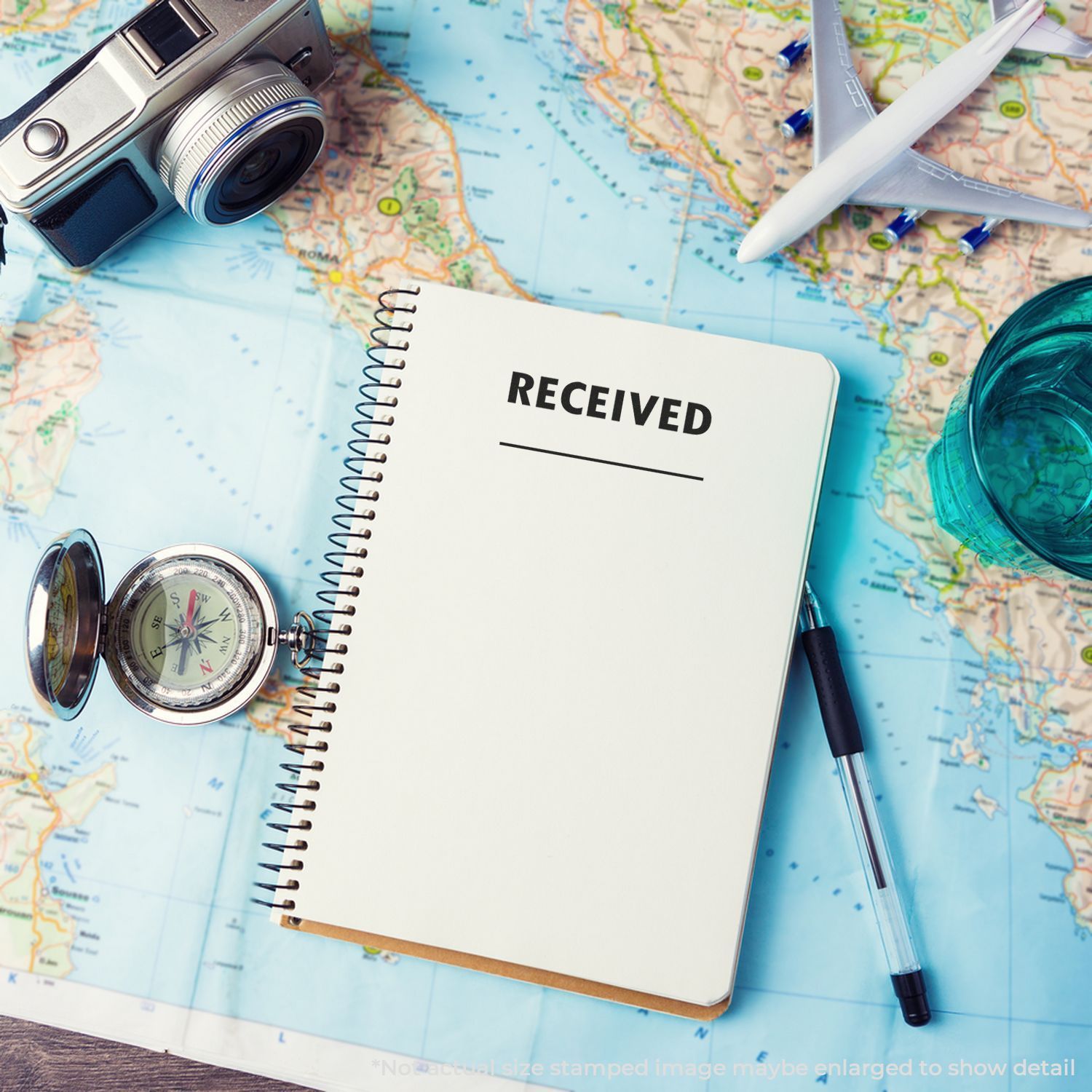 Travel itinerary notebook marked RECEIVED on a world map with compass, camera, pen and airplanebooking confirmation.
