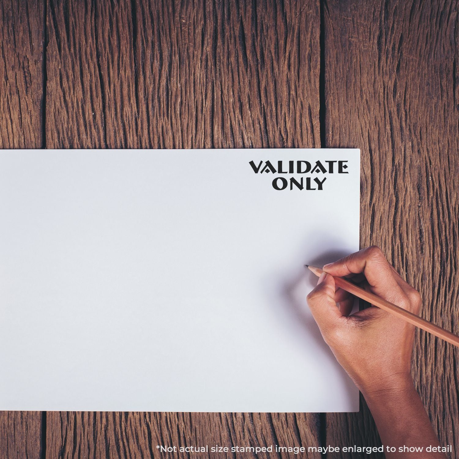 Hand holding a pencil over a blank paper with Validate Only text on a rustic wooden table.