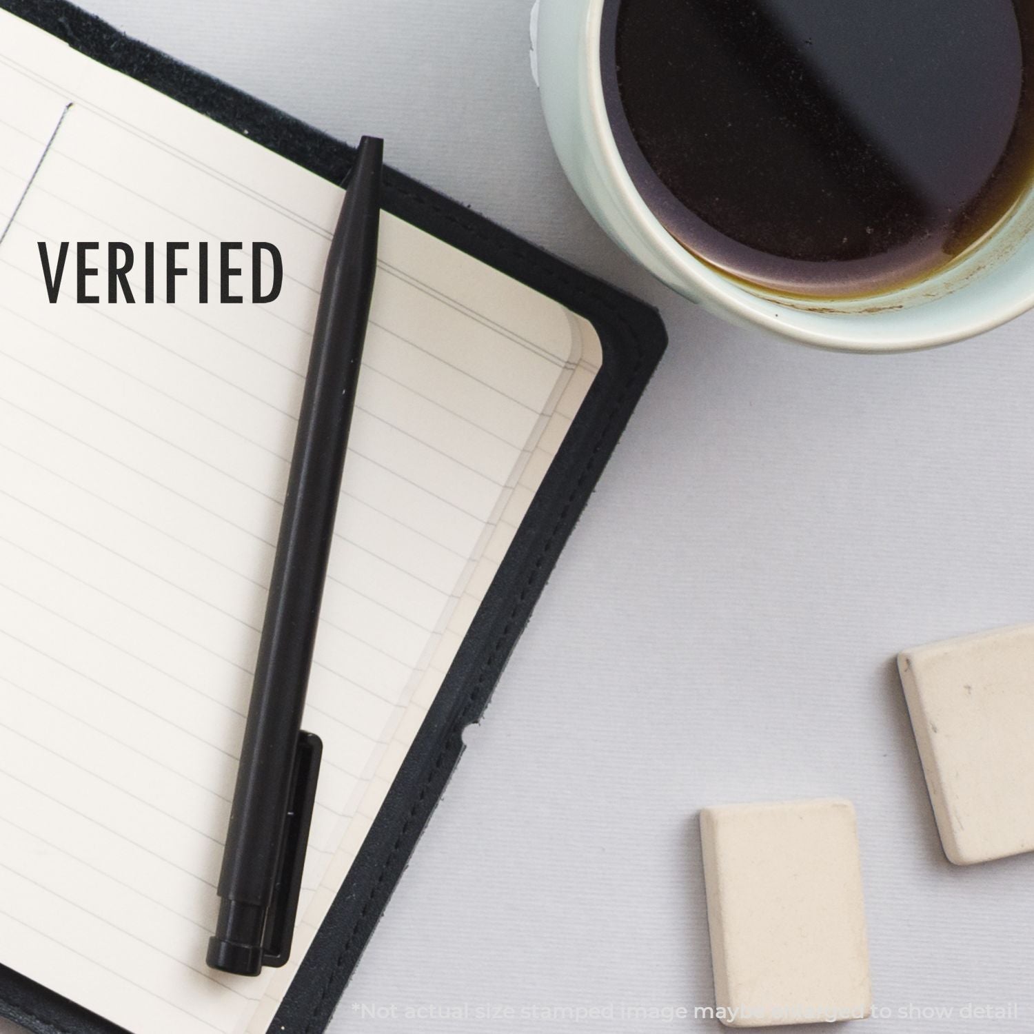 Verified stamp over notebook with coffee and pencil, symbolizing quality assurance, document review, and approval workflow.