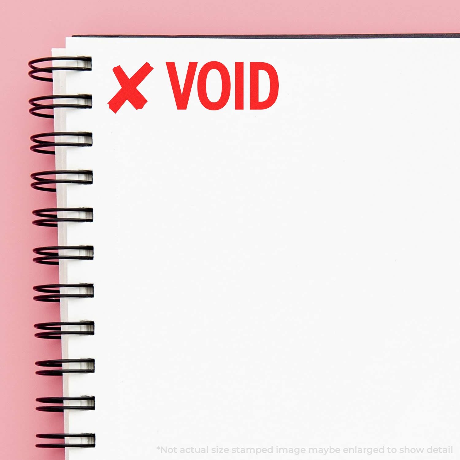 Close-up of spiral notebook page with red VOID stamp on pink background, blank paper with copy space.