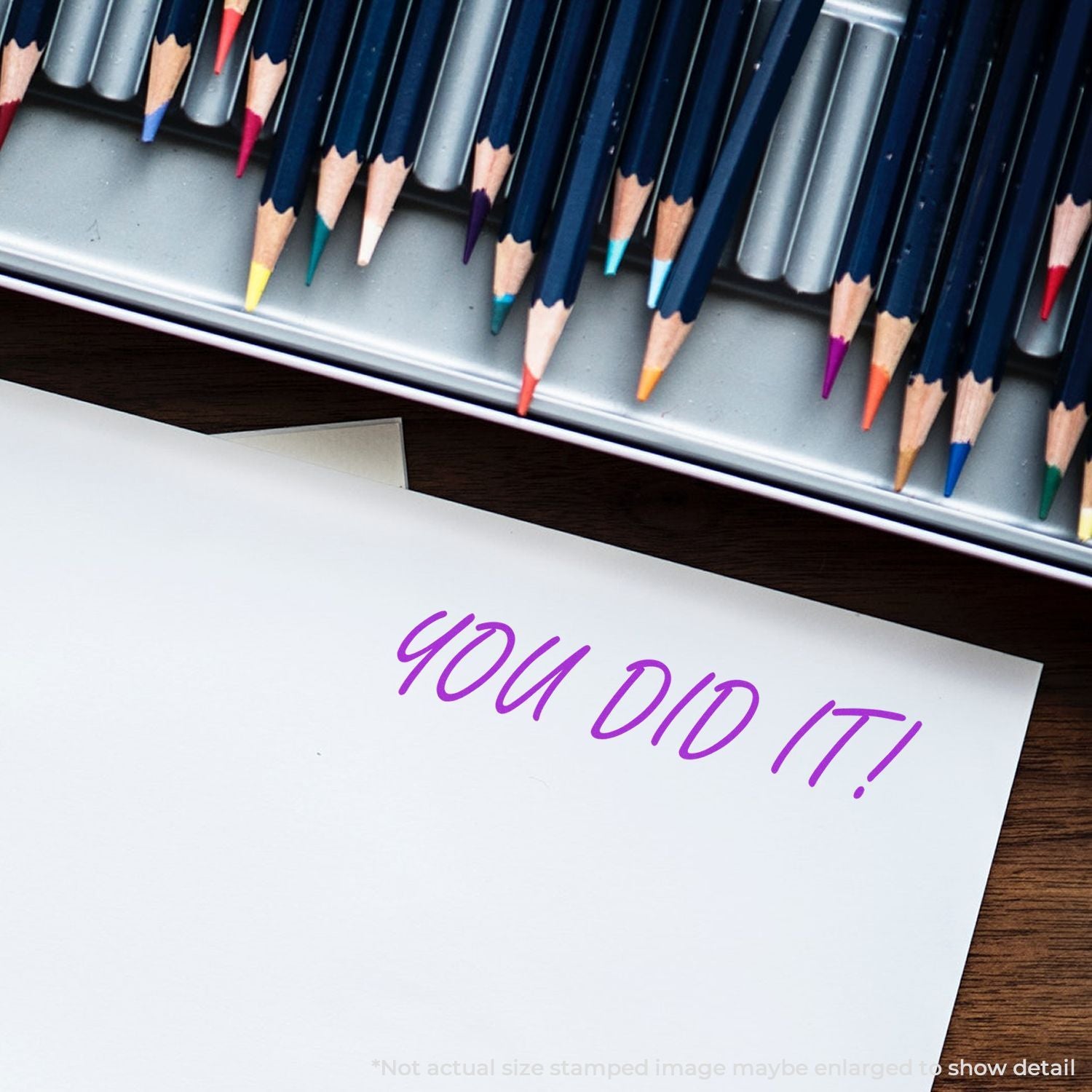 Colored pencils in a metal tray with a white sheet of paper reading YOU DID IT! in purple handwriting.