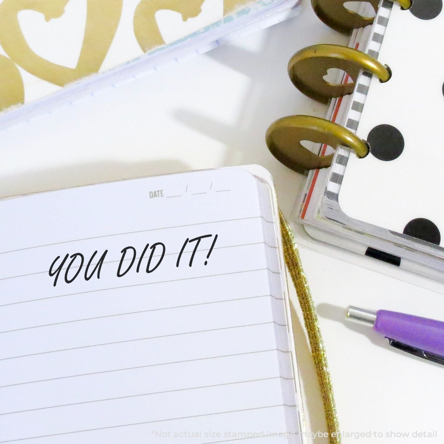 Open planner notebook with You Did It! motivational text, pen, and stylish stationery supplies on a white desk.
