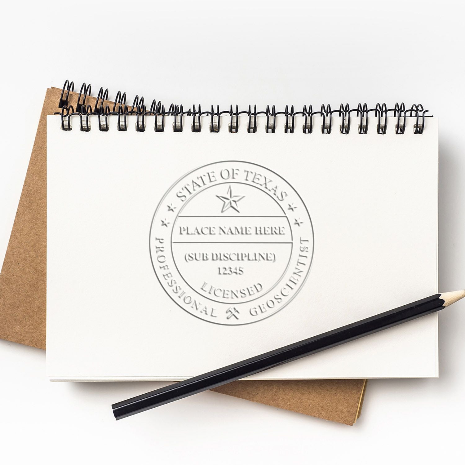 Spiral notebook with Texas State Professional Geoscientist seal, pencil, and blank workspace on a white background.