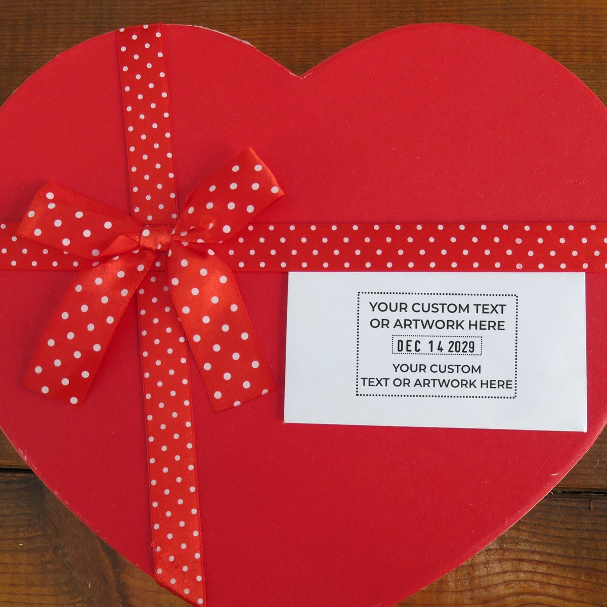Red heart-shaped gift box with polka dot ribbon and custom personalized label, perfect for Valentines Day gift packaging.