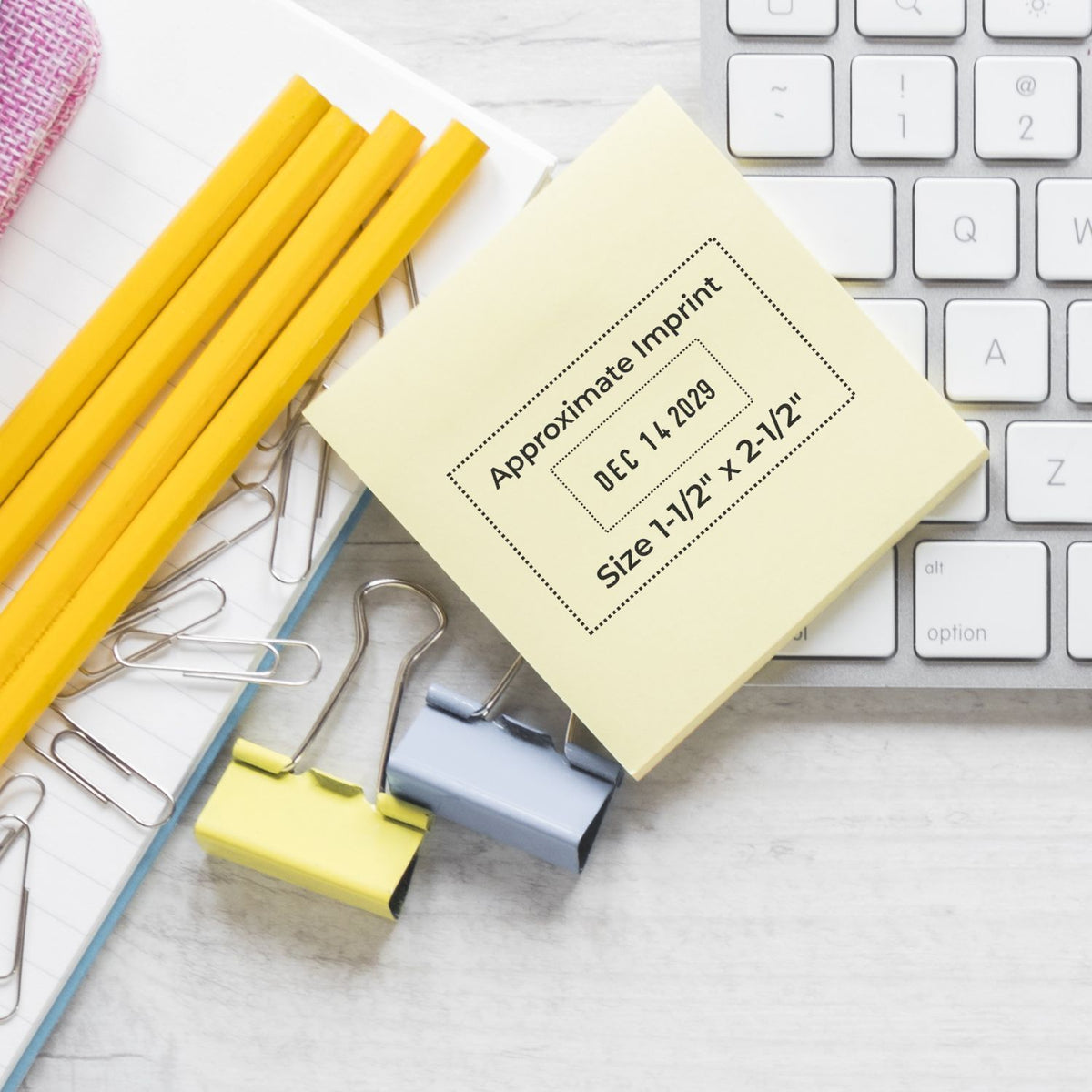 Office stationery flat lay with yellow pencils, binder clips, sticky notes, and computer keyboard with approximate imprint note.