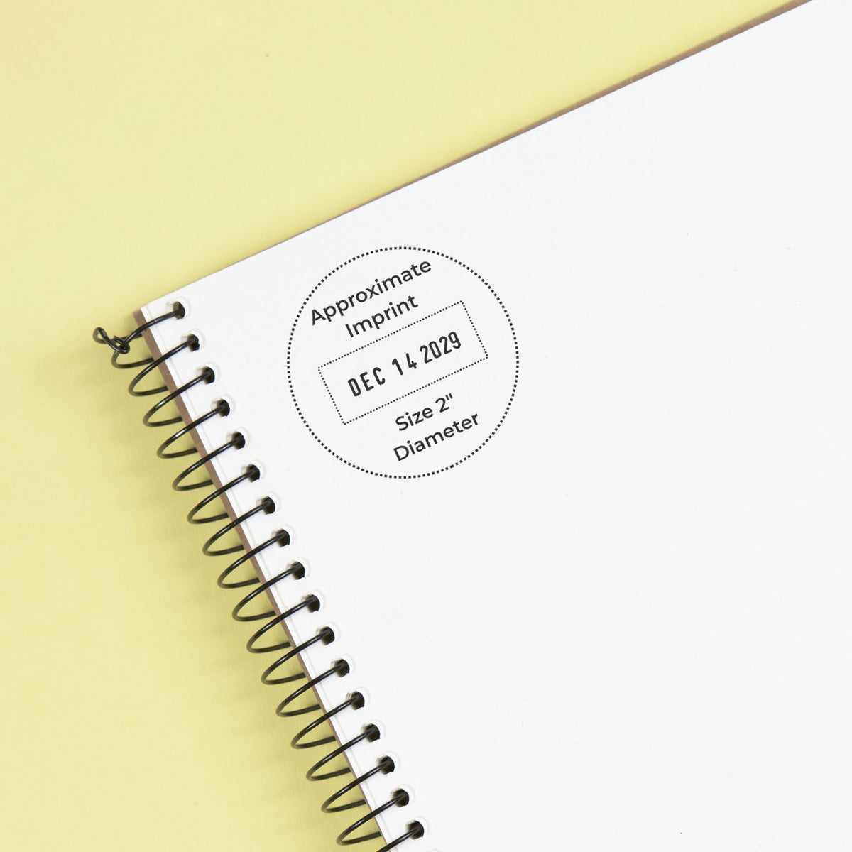 Spiral-bound notebook cover mockup with blank white pages and custom stamp imprint on a pastel yellow background.