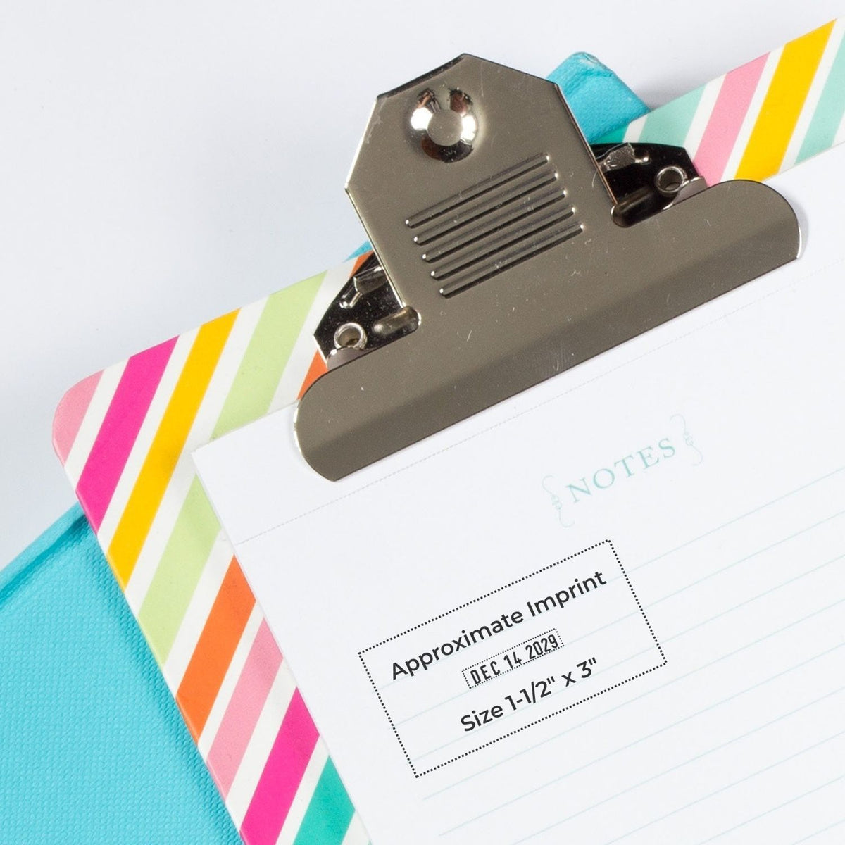 Colorful striped clipboard with notes paper and metal clip, close-up stationery mockup on blue background.