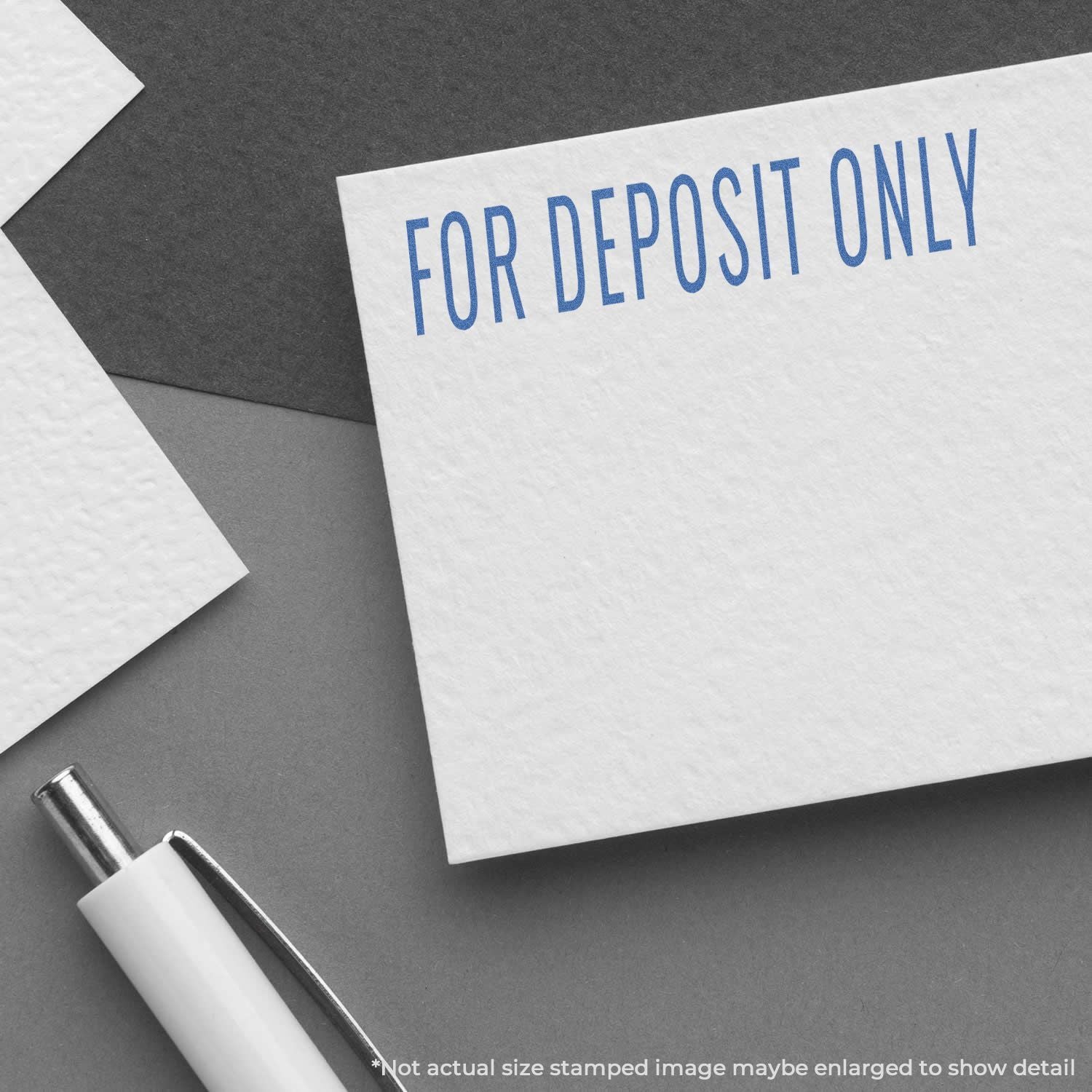 Deposit slip stamp FOR DEPOSIT ONLY in blue letters with pen on a dark background, showing restricted bank deposit use.