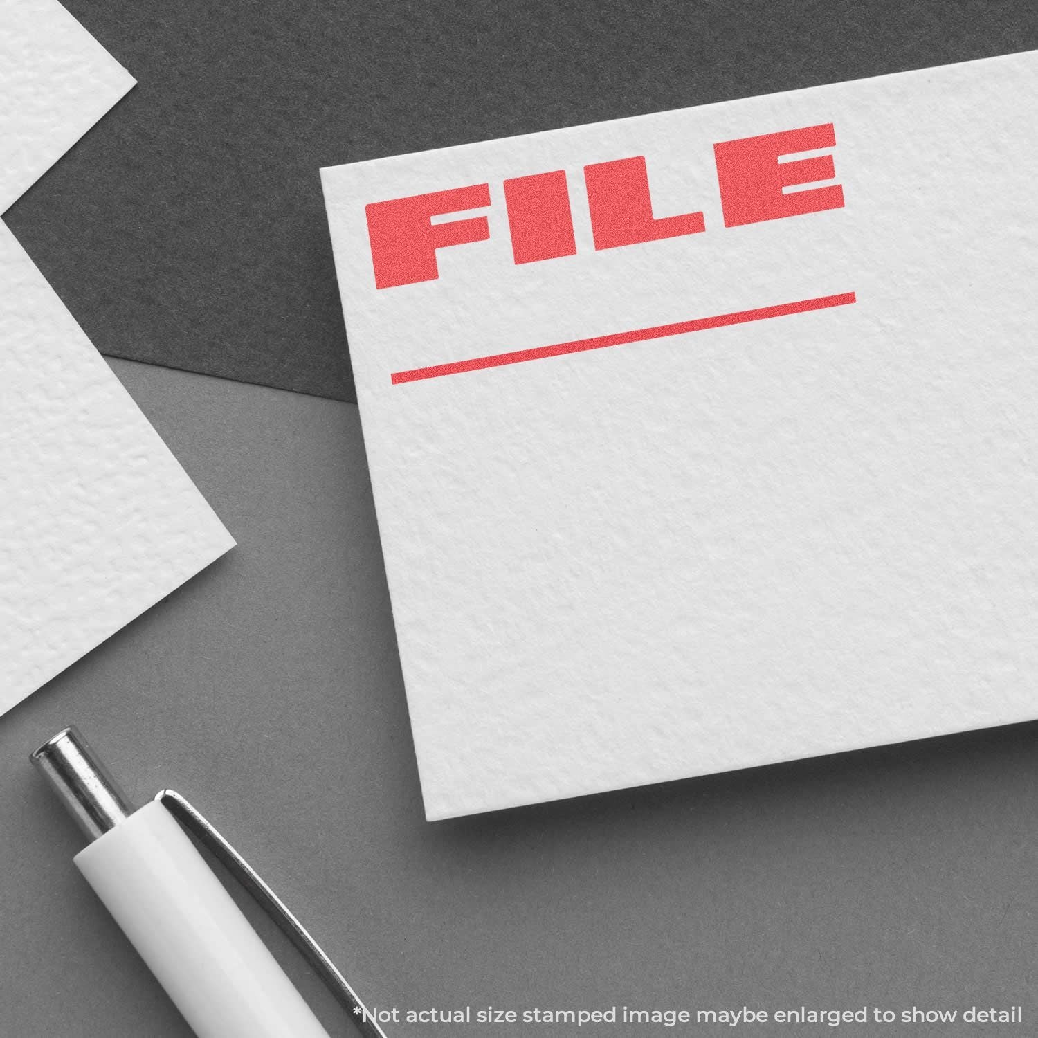 Office filing concept: a FILE document card in red letters on white paper with pen on gray background.