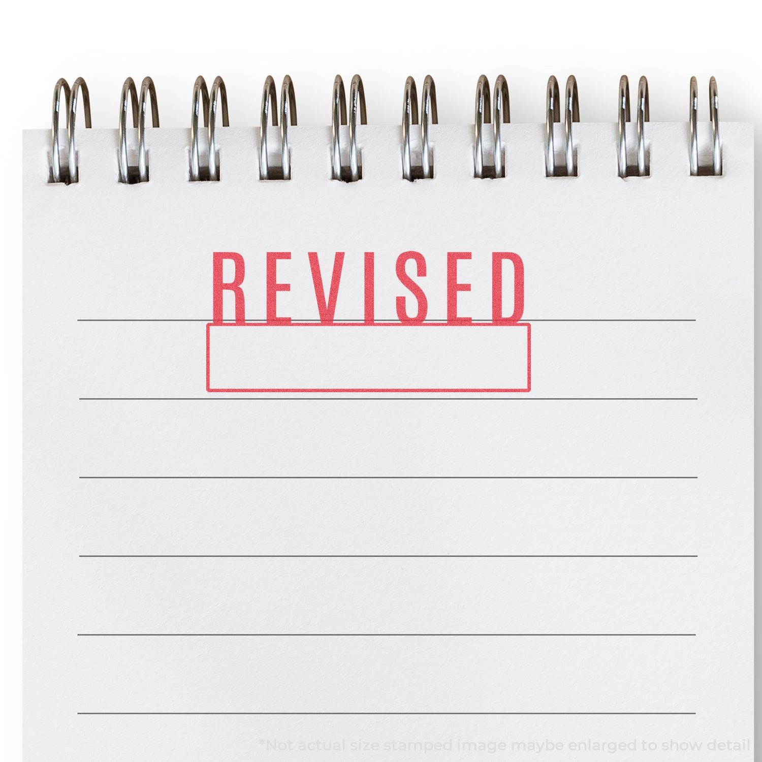 Red REVISED stamp over notebook lines with metal staples, indicating document updates and corrections.