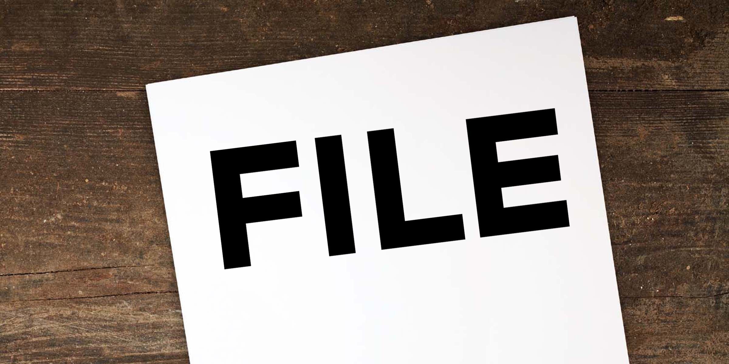 White paper with bold black “FILE” text on a rustic wooden background, representing document storage or file management