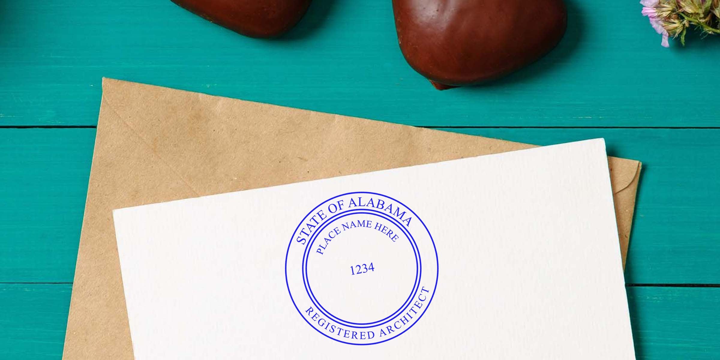 Alabama architect seal on white paper with envelope, placed on teal wooden table, showcasing the seal and design guidelines.