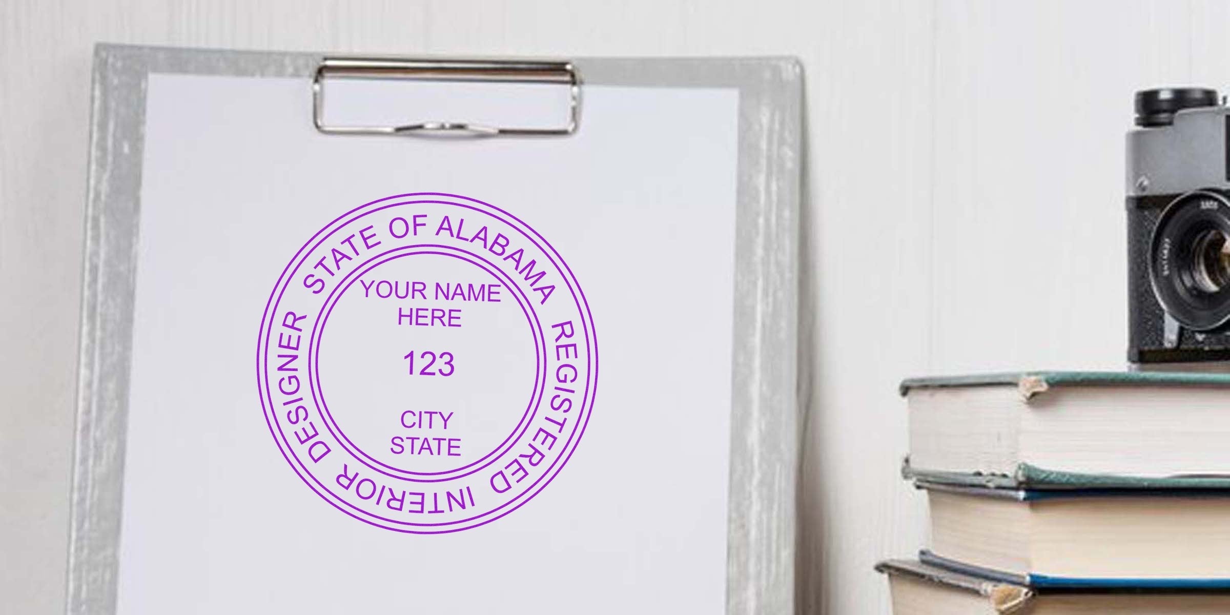 Official Interior Designer Certification Alabama stamp on clipboard with vintage camera and stacked books, displaying Interior Designer Seal Alabama.