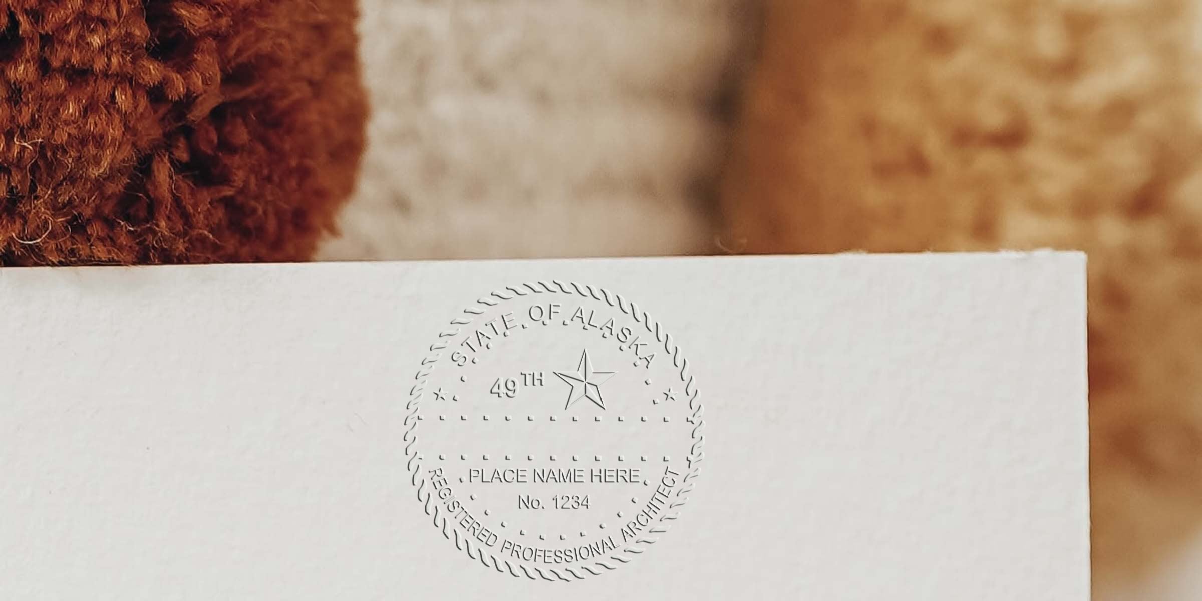 Close-up of a custom architect seal with the State of Alaska registered professional architect embossed on white paper.