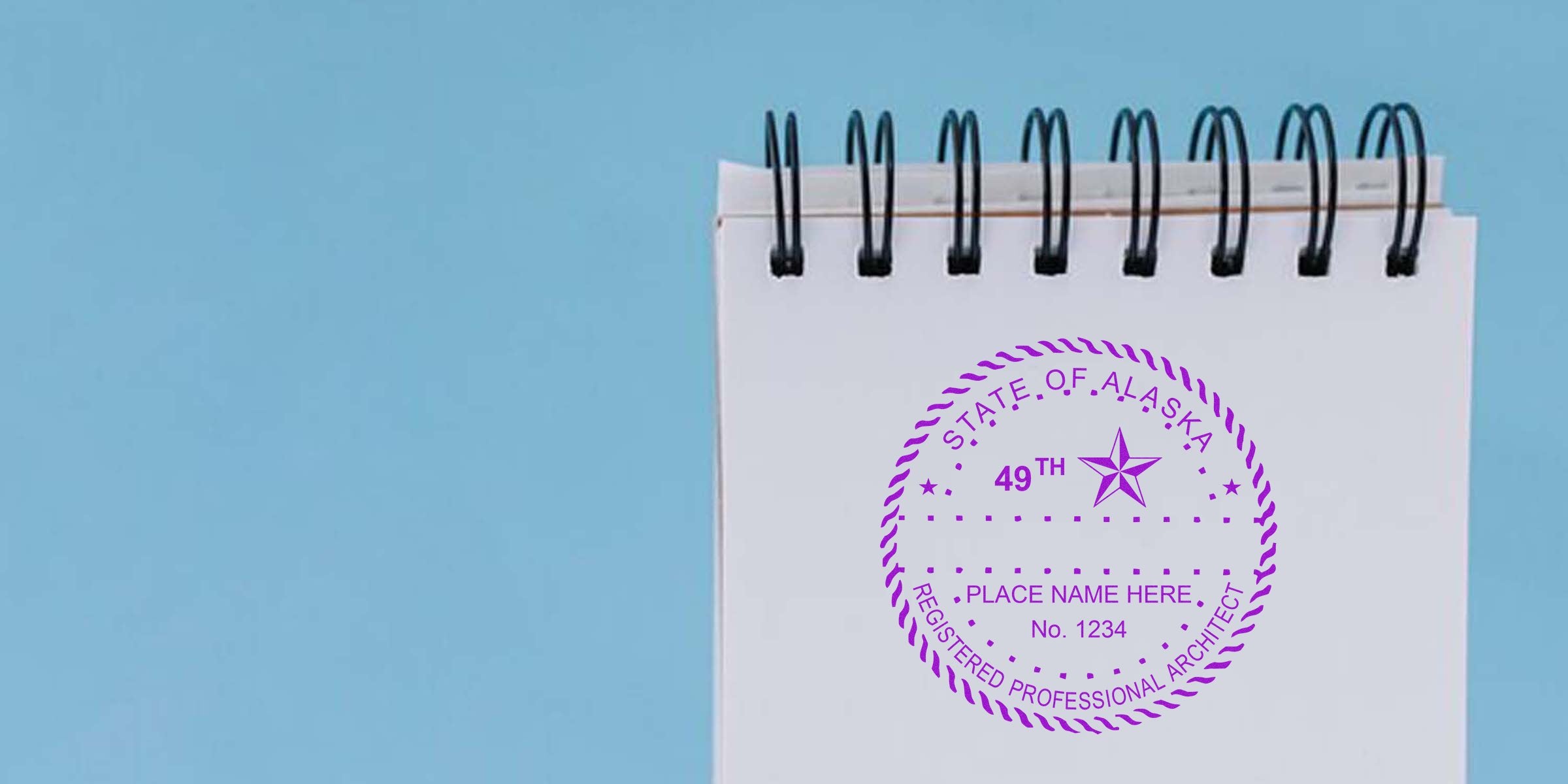 Alaska architect license stamp and professional architect seal on a spiral notebook against a blue background.