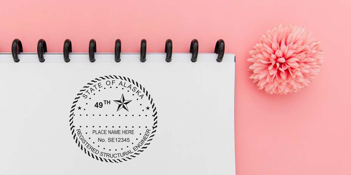 Alaska PE Embossing Seal and Engineer Embossing Stamp on a white notebook with a pink flower background.