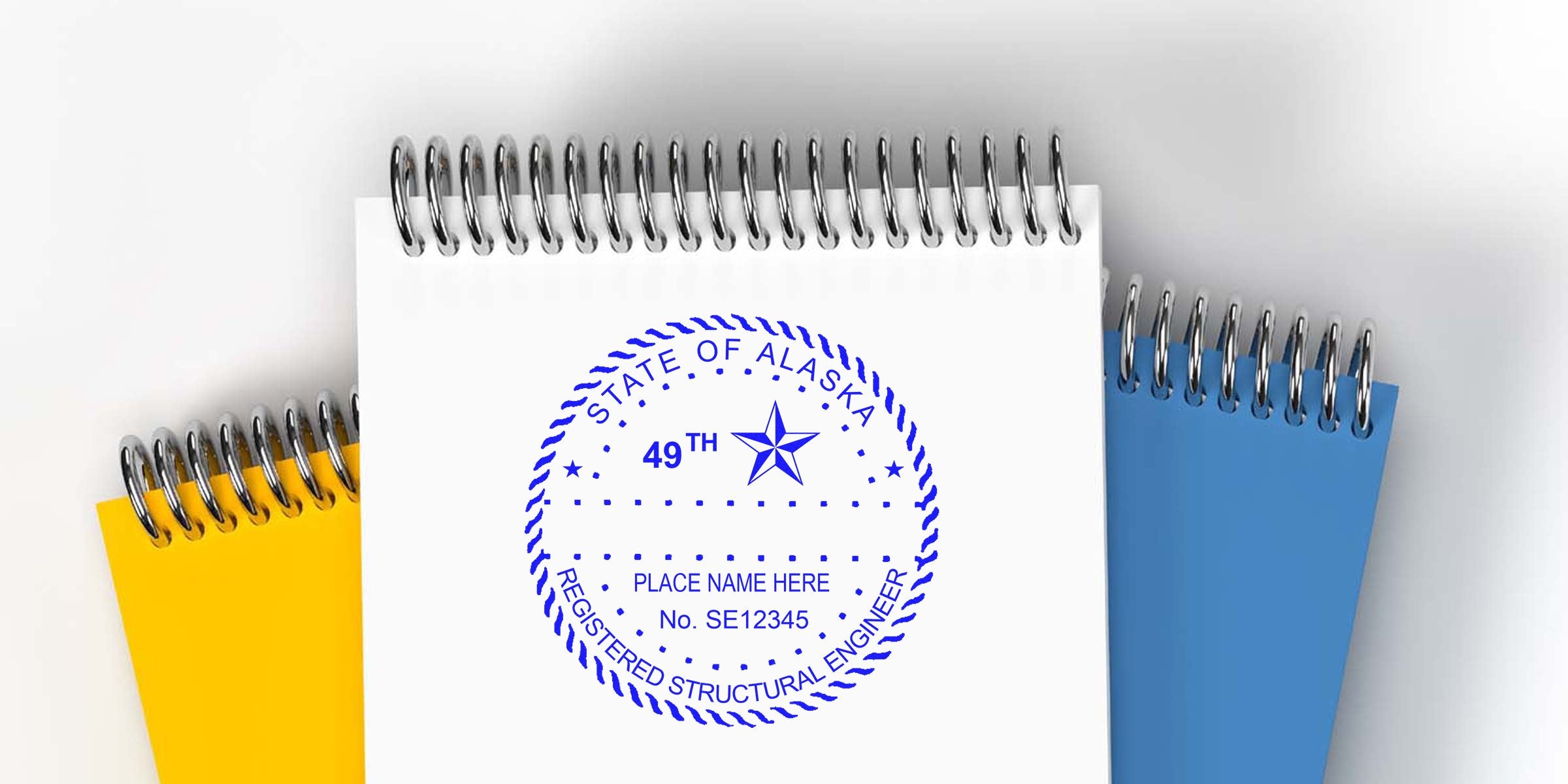 Alaska engineer stamp on spiral notepad with blue and yellow covers, displaying professional engineer seal requirements.