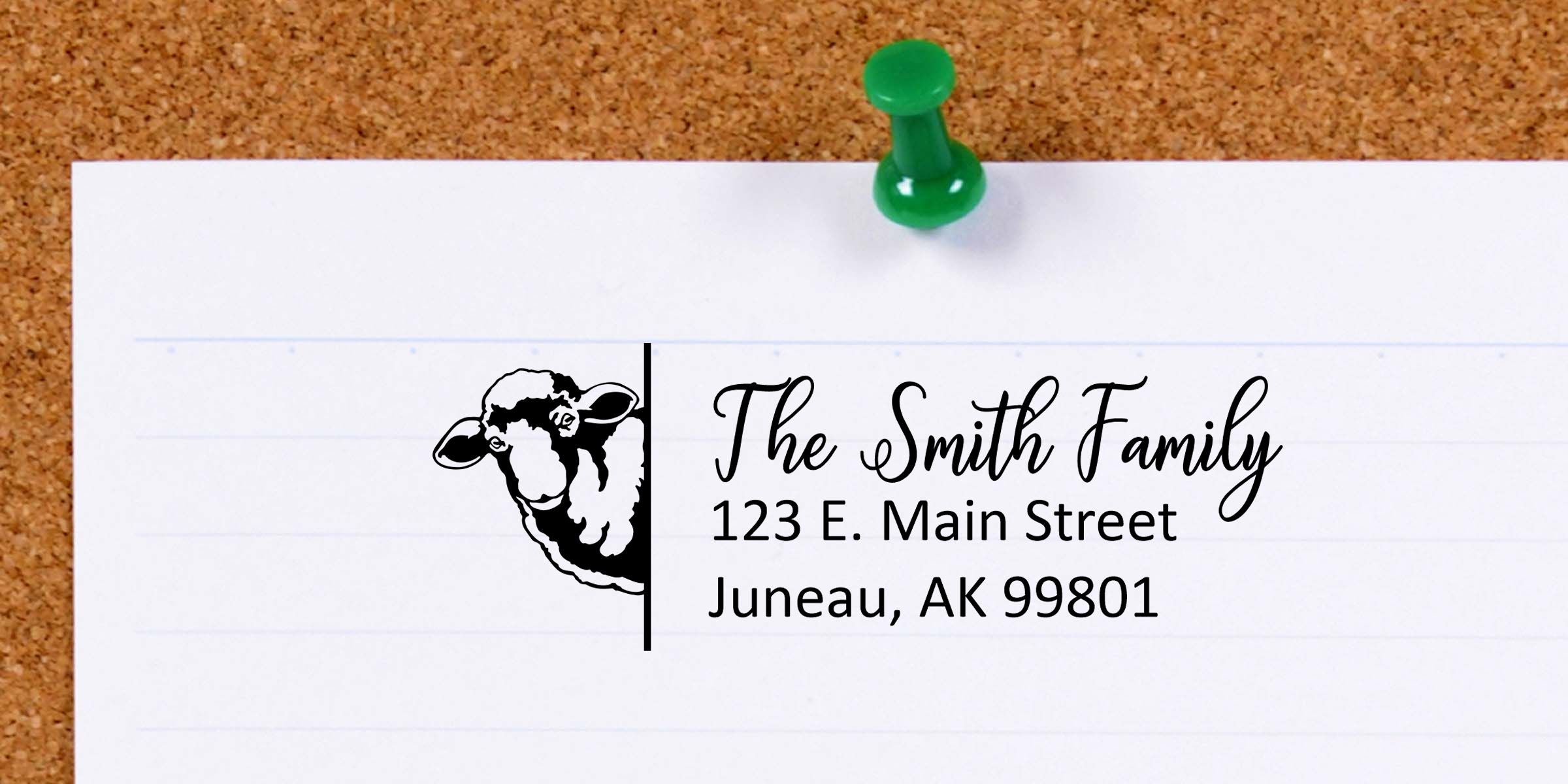Customized family return address label with sheep logo, reading The Smith Family, 123 E. Main Street, Juneau, AK 99801, pinned to a corkboard with a green pushpin.