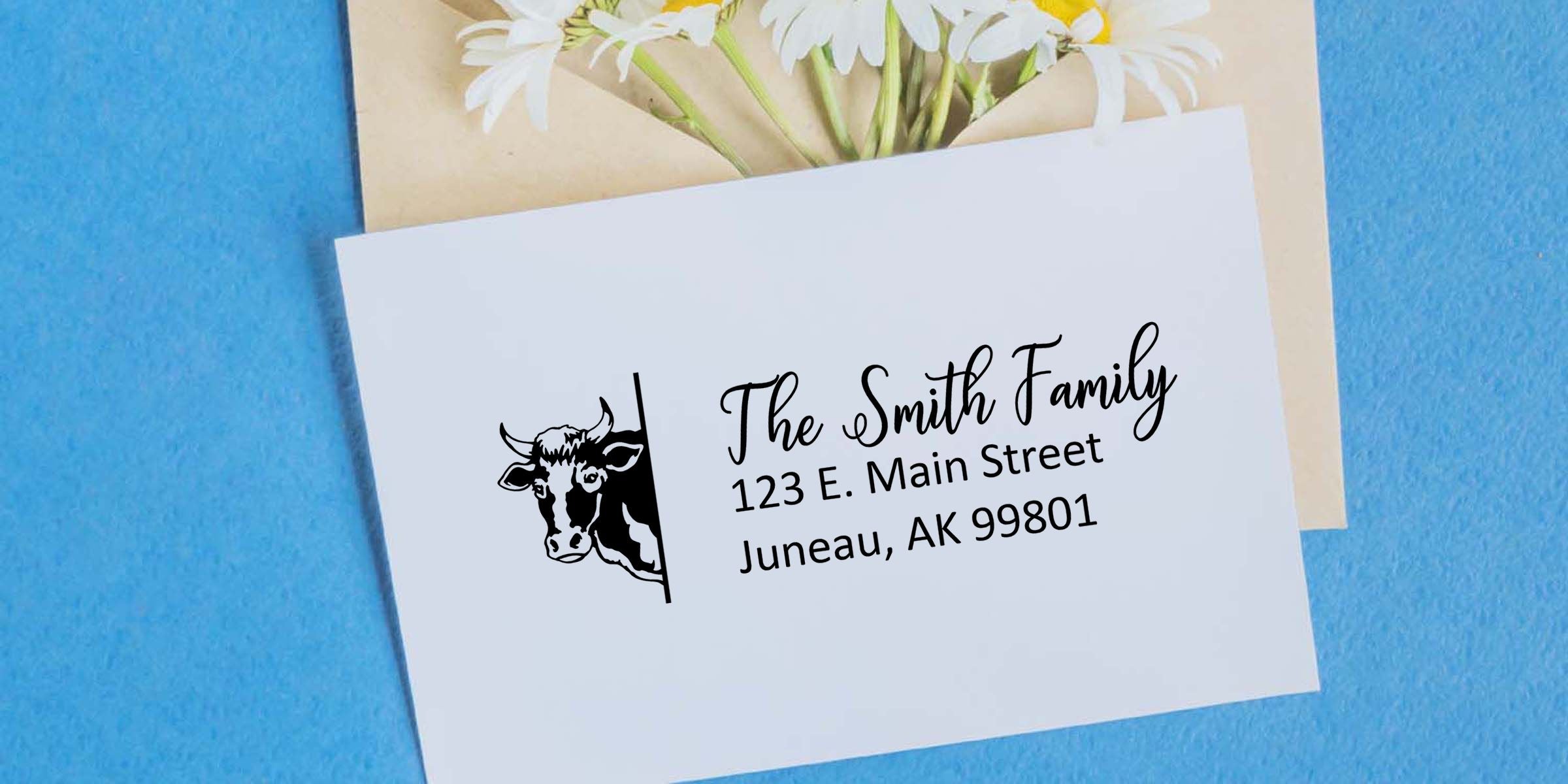 Personalized family address card with cow logo, “The Smith Family” mailing address, white daisies, and blue background