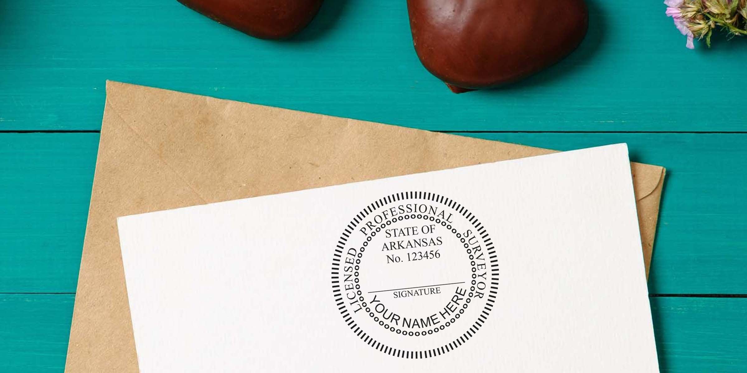 Arkansas land surveyor stamp and certification on white paper with envelope, placed on a turquoise wooden table.