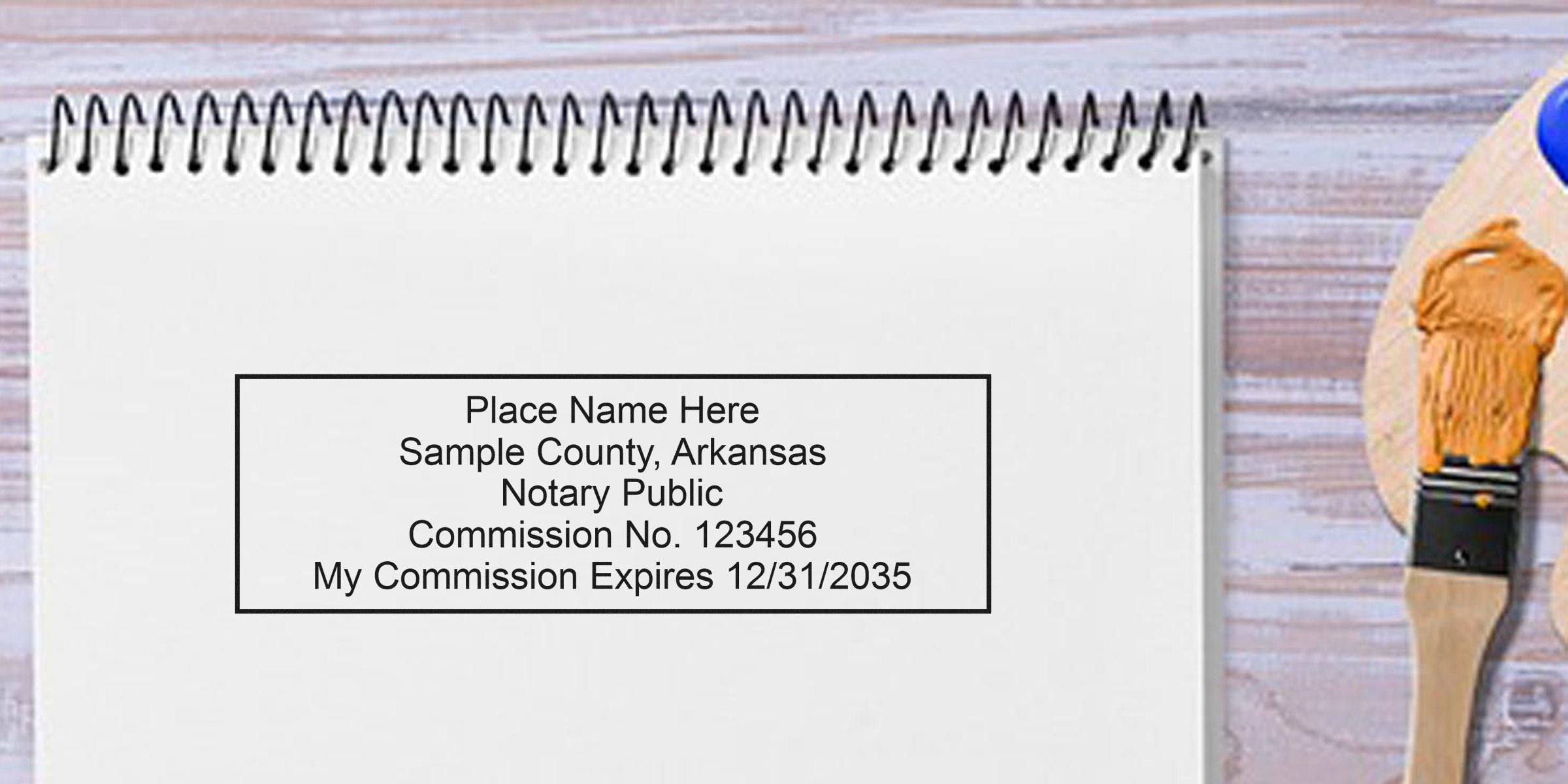 Sample Arkansas notary seal on white notebook page showing notary public commission stamp with expiration date, meeting Arkansas notary seal requirements.