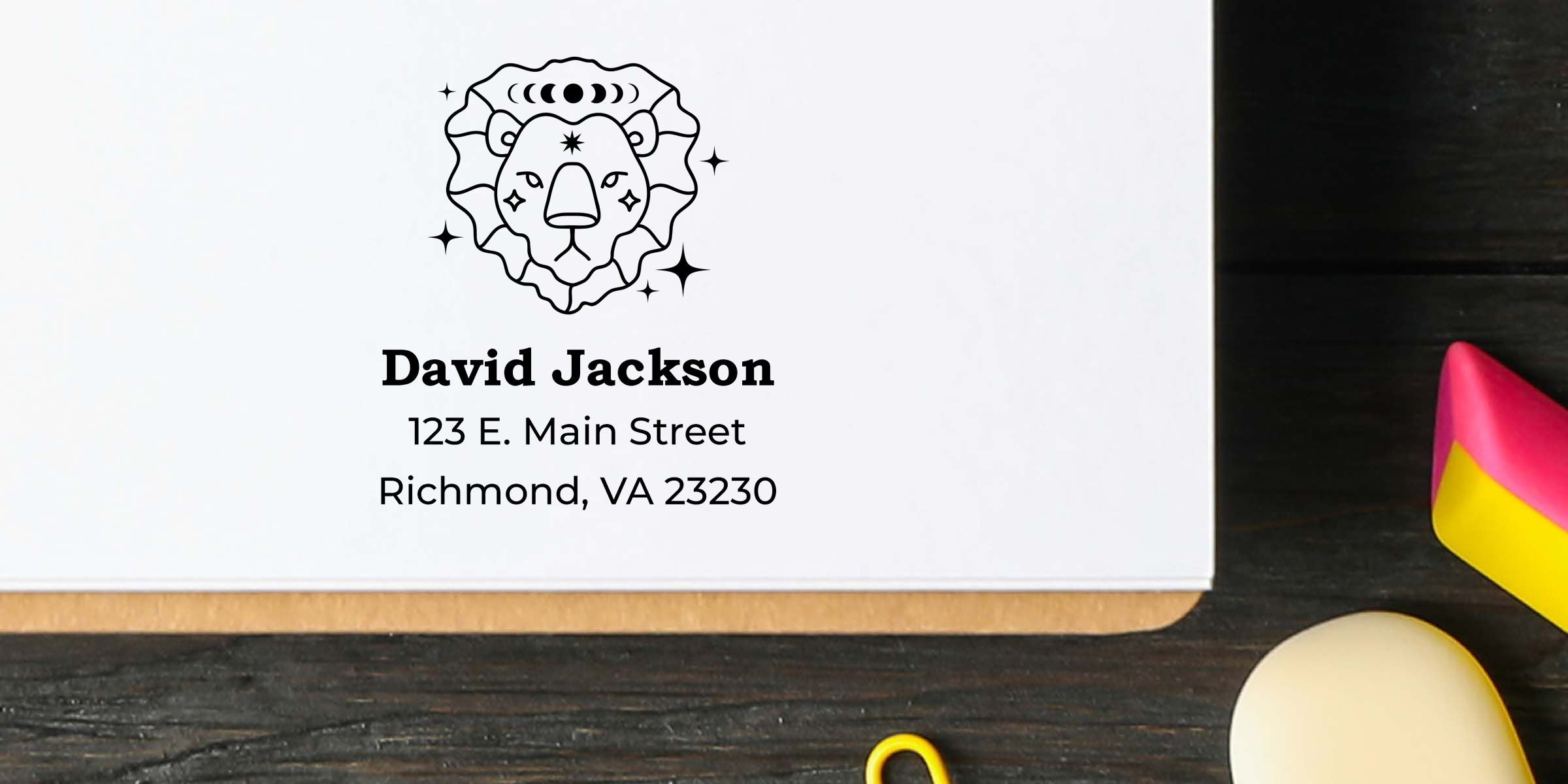 Custom lion crest wedding invitation envelope addressed to David Jackson, 123 E. Main Street, Richmond, VA 23230, on a white card with black lettering and a dark wood background.