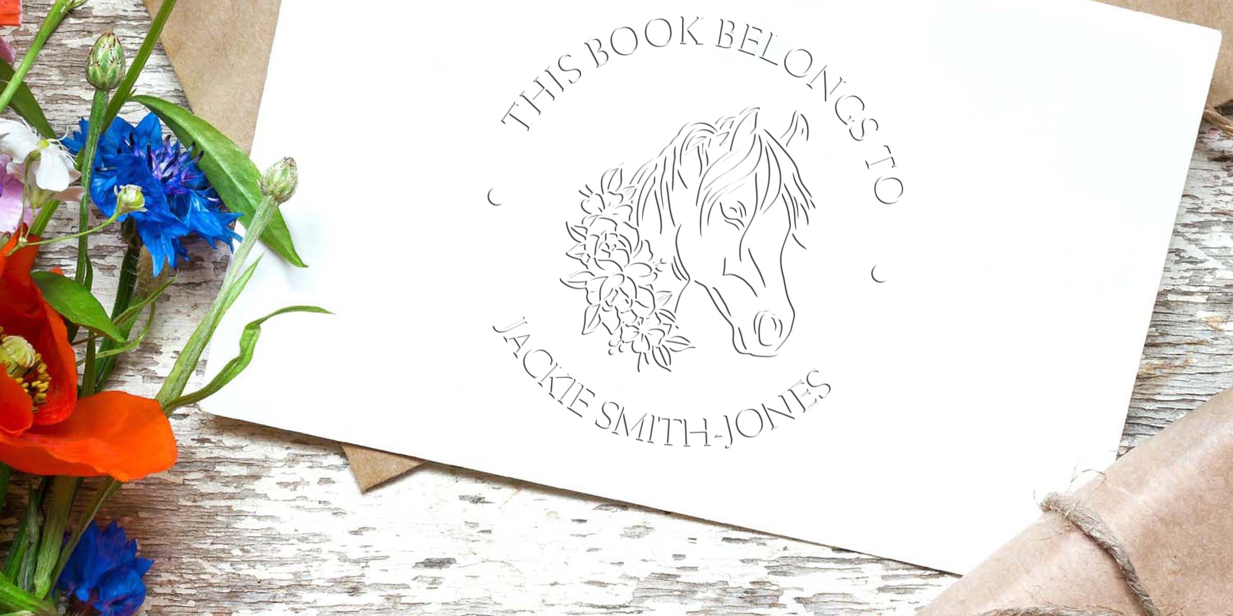 Personalized horse-themed bookplate with floral accents reading “This Book Belongs to Jackie Smith-Jones” on a rustic wooden background