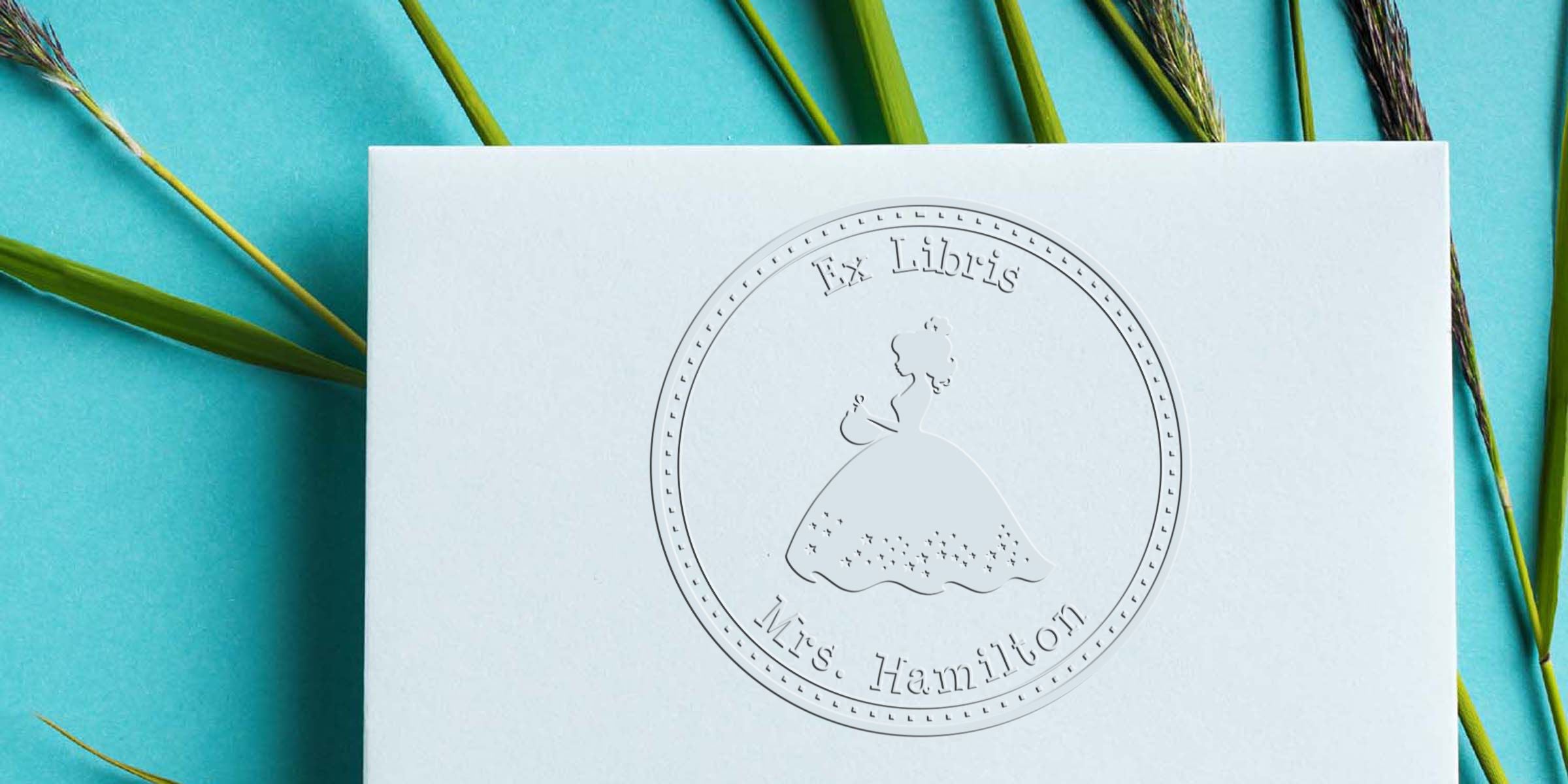 Embossed Ex Libris Mrs. Hamilton personalized bookplate on white stationery with turquoise background and green reeds