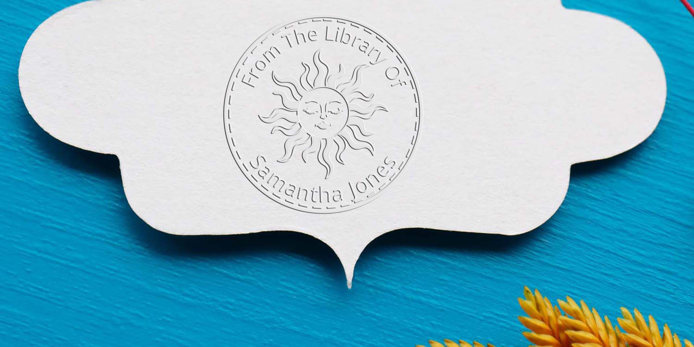 White embossed bookplate label with “From The Library Of Samantha Jones” sun logo on a bright blue textured background with yellow leaves