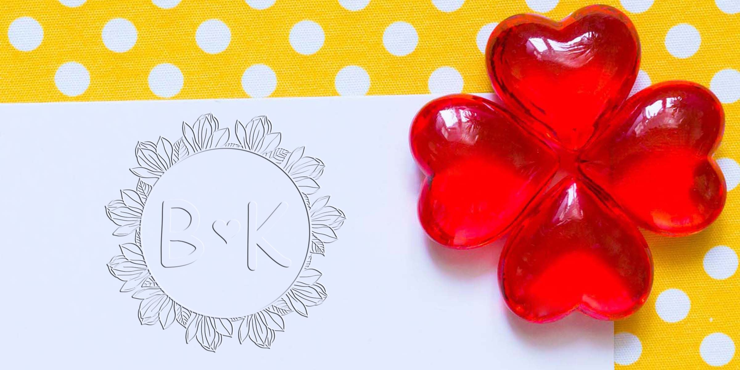 Translucent red flower-shaped decorative gem beside a personalized monogram card on a yellow polka dot background
