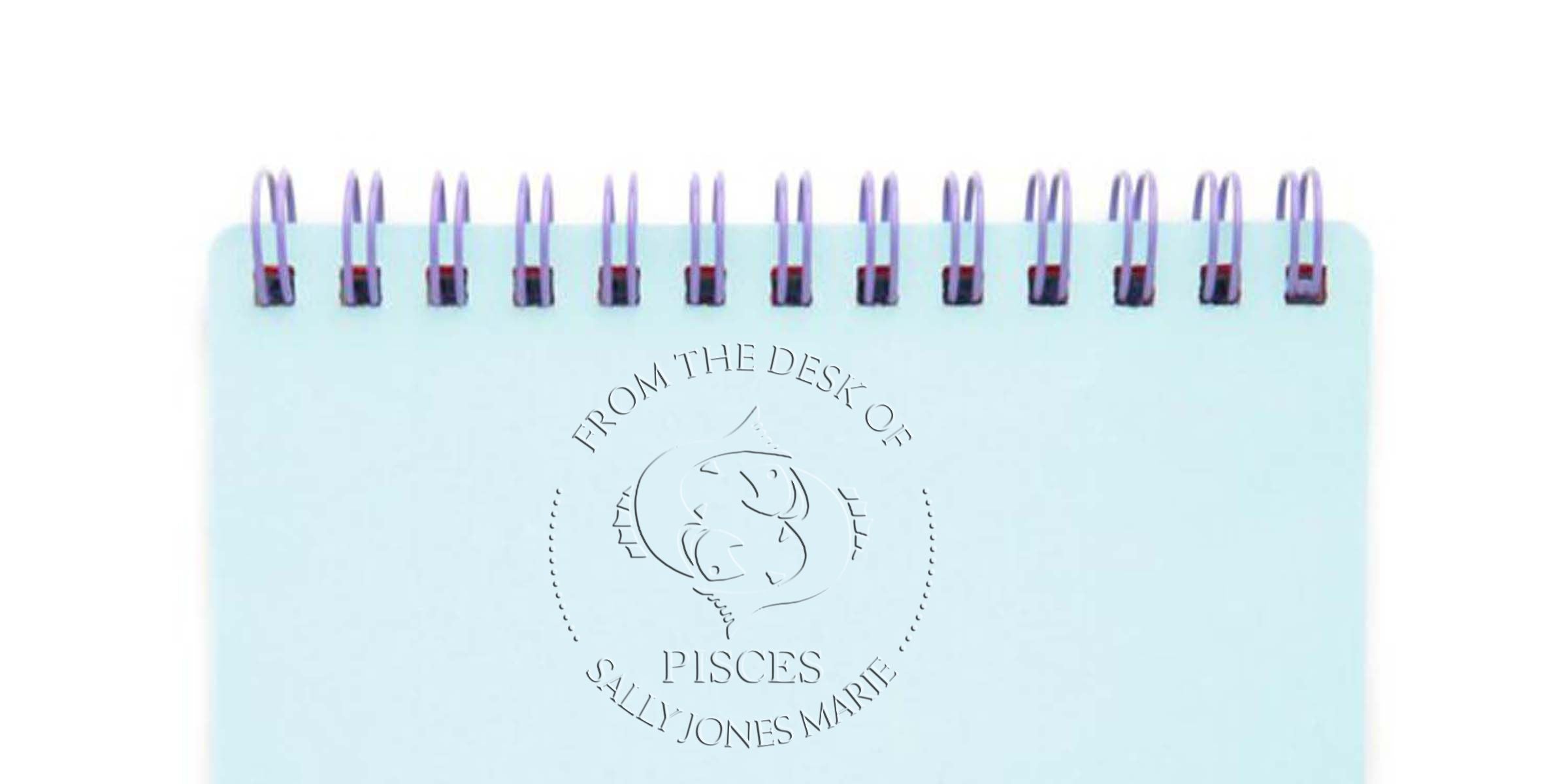 Light blue spiral notebook with embossed Pisces zodiac design and “From the Desk of Sally Jones Marie” text on the cover