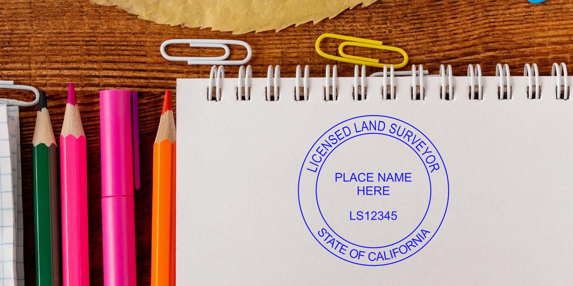 California land surveyor stamp on white notebook with colorful pencils and clips on wooden desk, showing the official state seal for land surveying certification and quick stamp order tips.