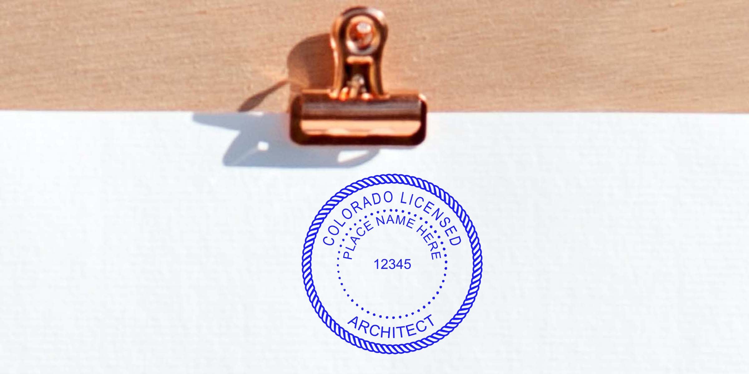 Colorado architect stamp on white paper with copper clip, showing licensed architect seal for application.