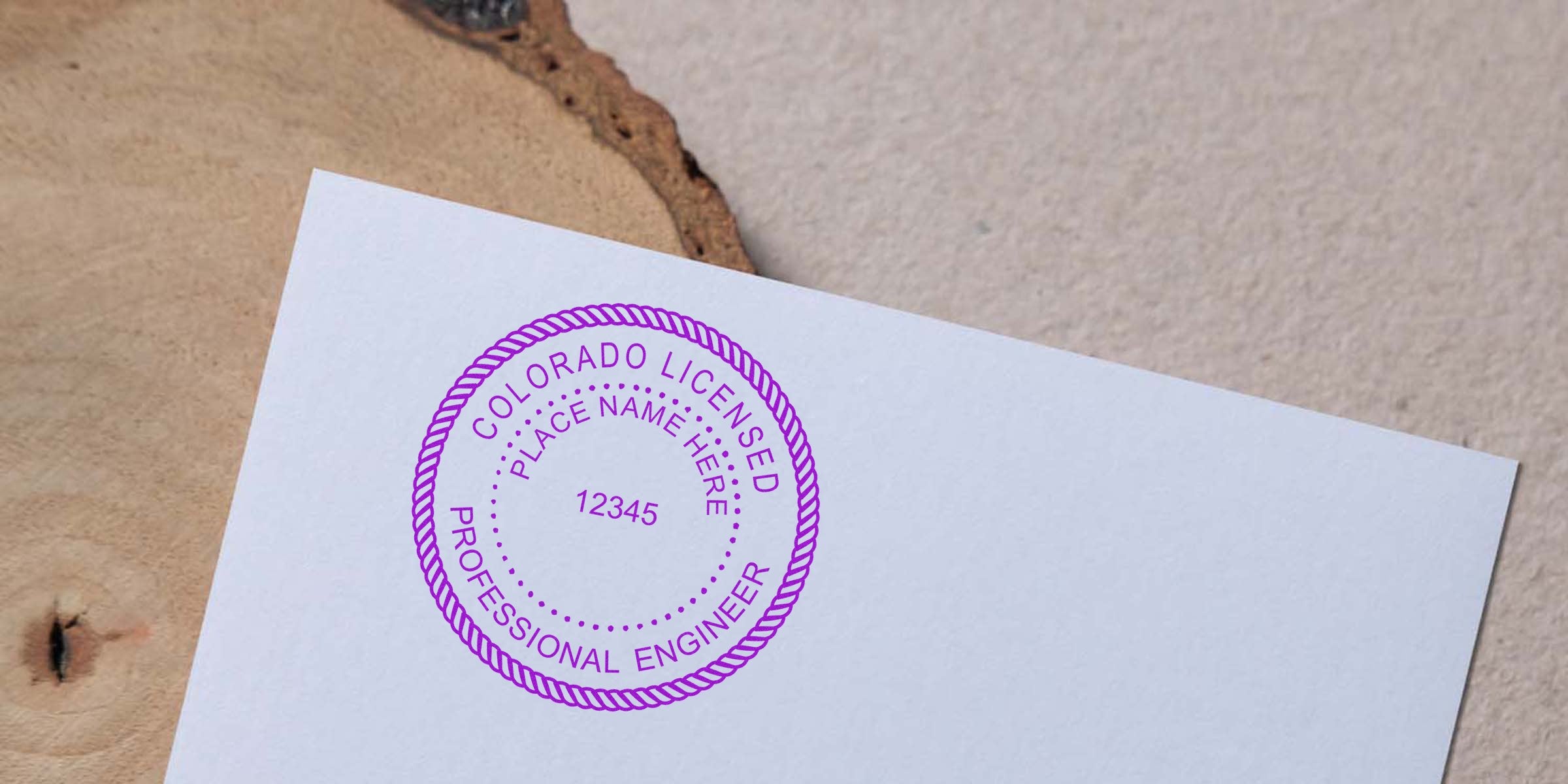 Colorado engineer embossing a stamp on white paper, meeting Colorado engineering seal requirements.