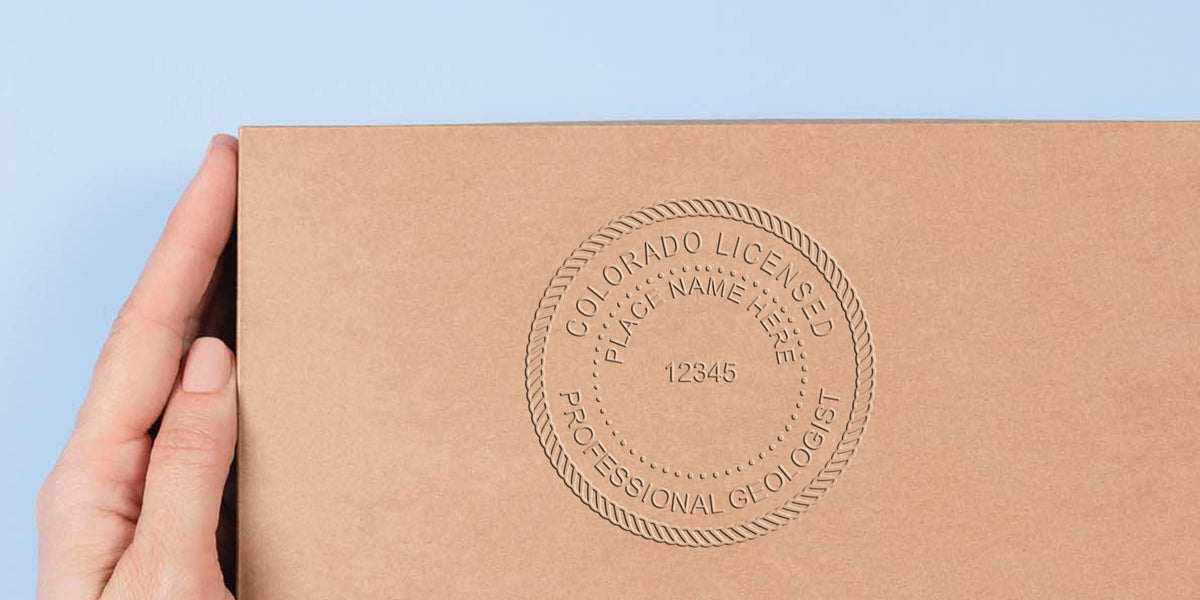Hand holding a cardboard box with an embossed Colorado geologist seal, certification number, and detailed seal design.