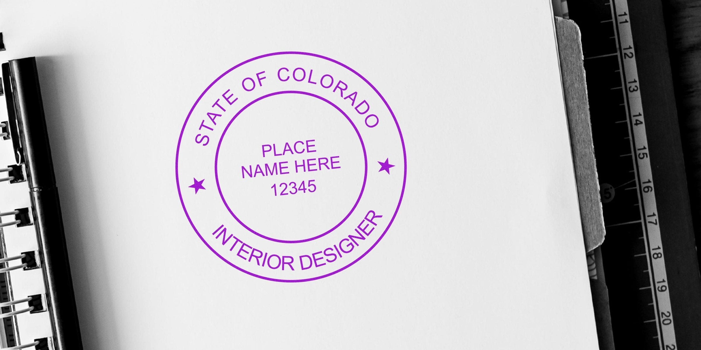 Colorado interior designer’s stamp on white paper with clipboard and ruler, highlighting interior design certification in Colorado.