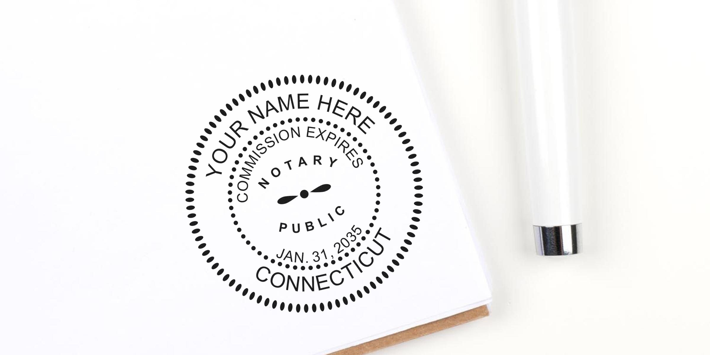 Custom CT notary supplies with personalized stamp on white paper, pen, Connecticut seal, and official commission expiration date—ideal for upgrading your notary toolkit.