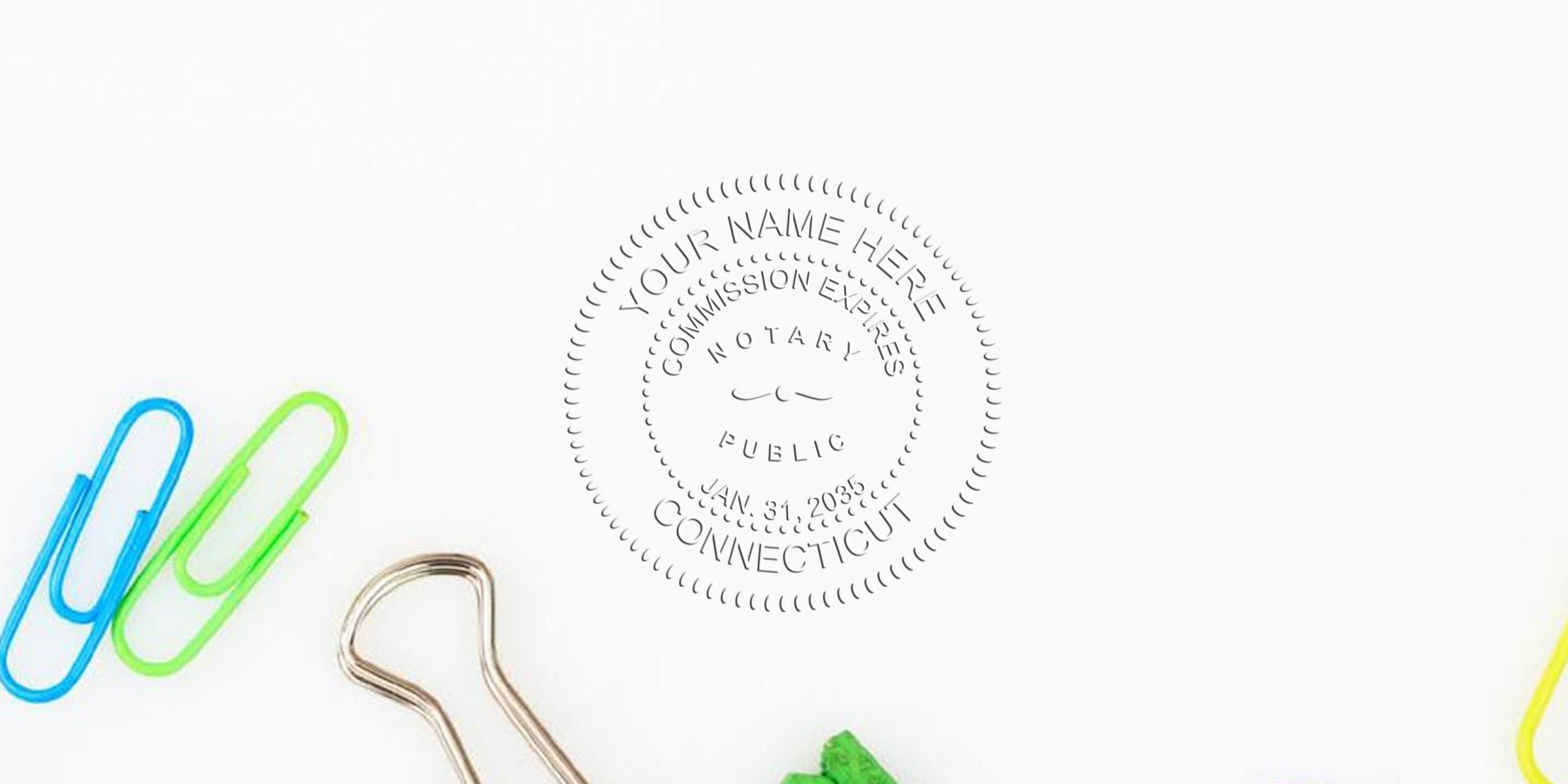 Connecticut notary starter kit with a notary public stamp showing commission expiration, surrounded by colorful paper clips and a binder clip on a white background, representing the notary journey in Connecticut.