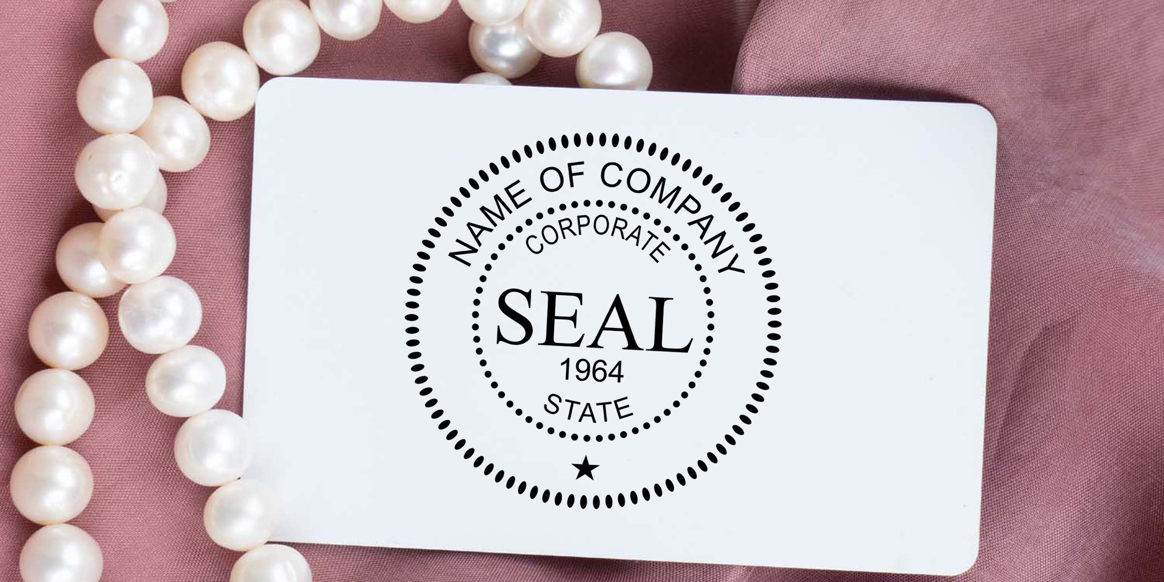 White corporate seal stamp card on pink fabric with pearl necklace accents