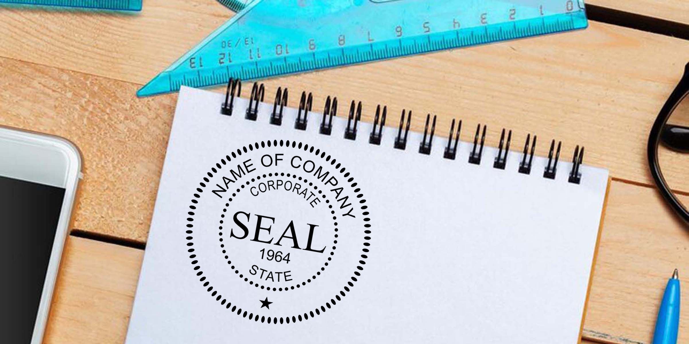 Notebook with corporate seal stamp design on a wooden desk, surrounded by a blue ruler, smartphone, pen, and glasses for business branding and document approval concept