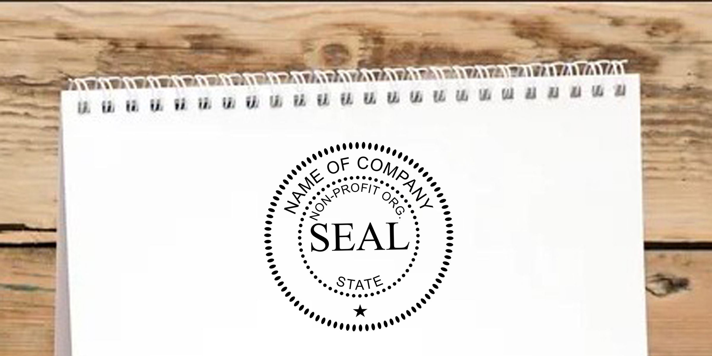 Blank spiral notebook with a custom company seal logo mockup on a rustic wooden table, featuring “Name of Company,” “Non-Profit Org.,” and “State” text design.