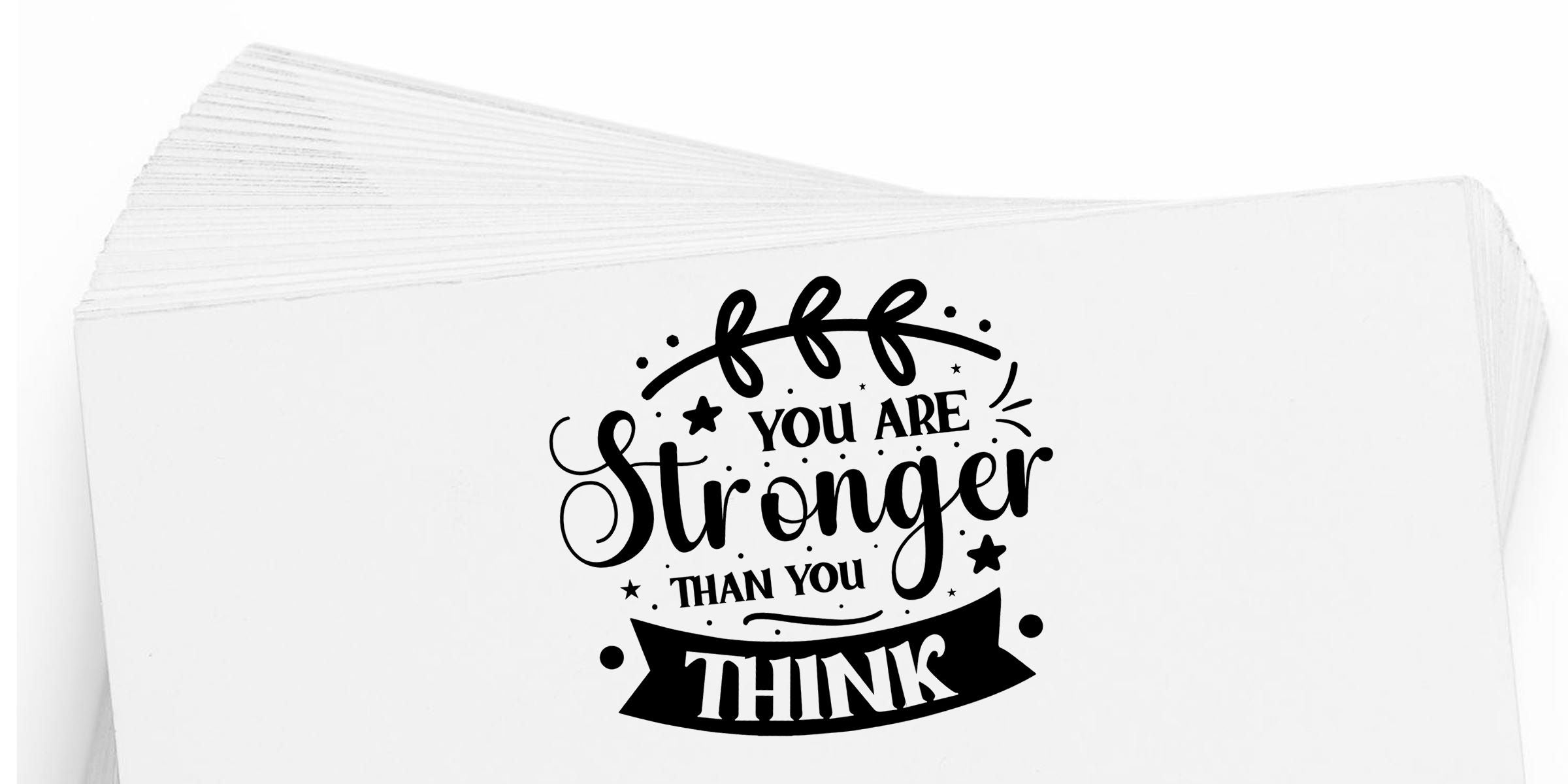 Stack of white napkins with black motivational quote design reading “You Are Stronger Than You Think” on a clean white background