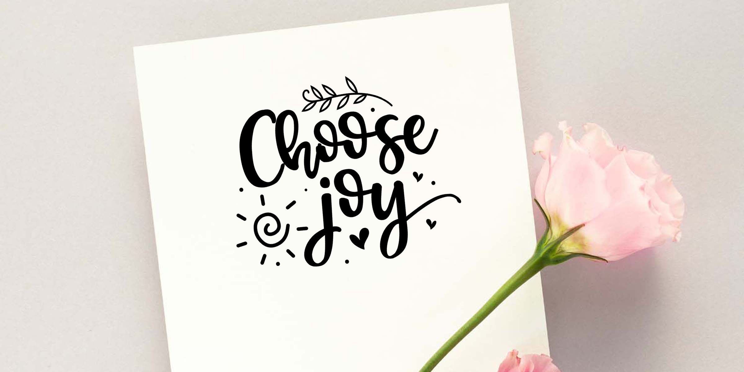 Hand-lettered “Choose Joy” quote card with floral accents and a pink rose on a soft white background