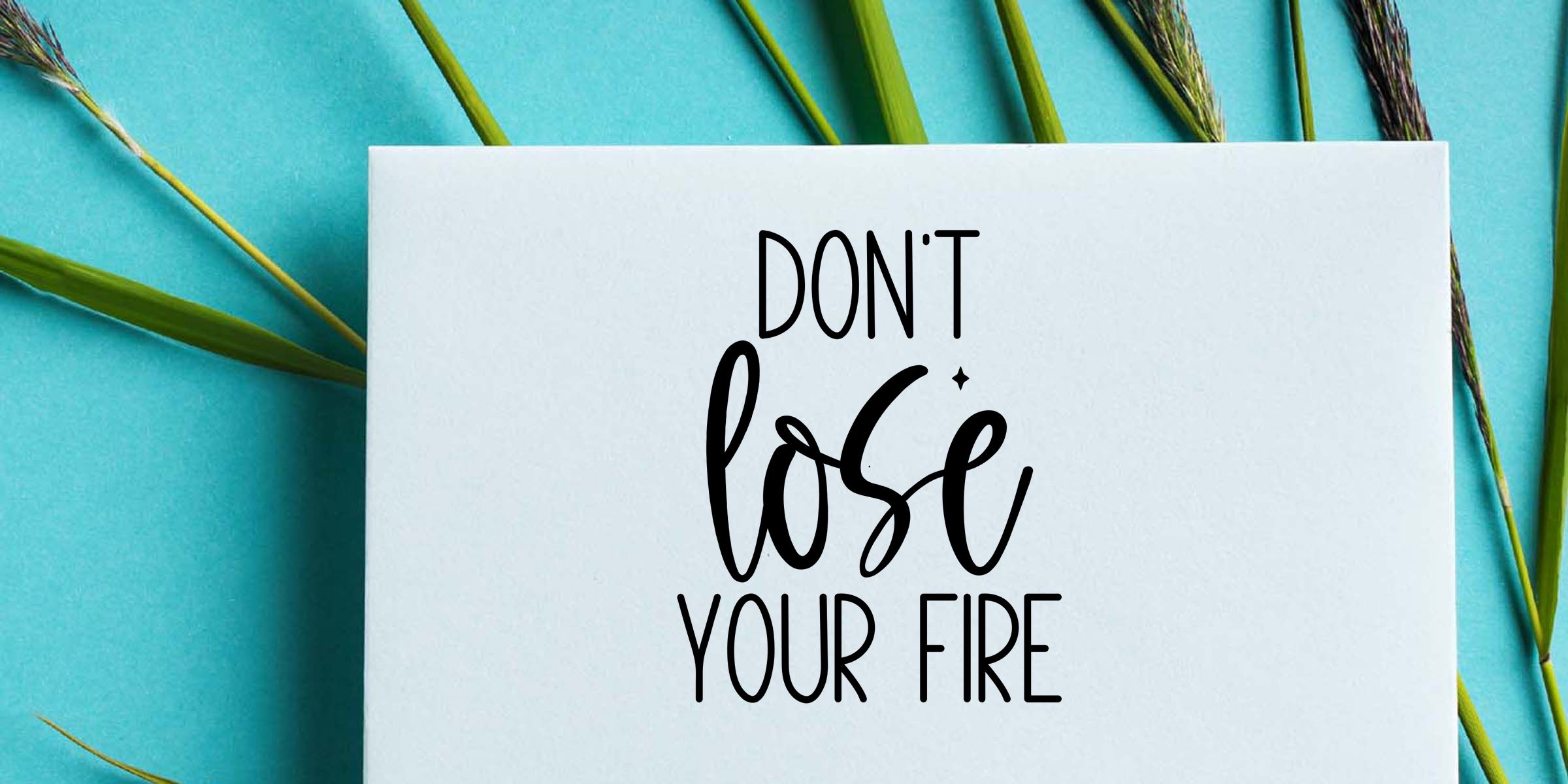 Motivational quote card reading “Don’t lose your fire” on a white background with green grass stems over a turquoise backdrop